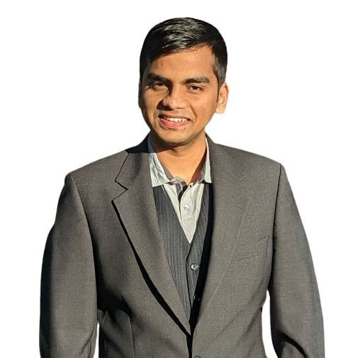 Man in a gray suit and tie standing and smiling against a white background.